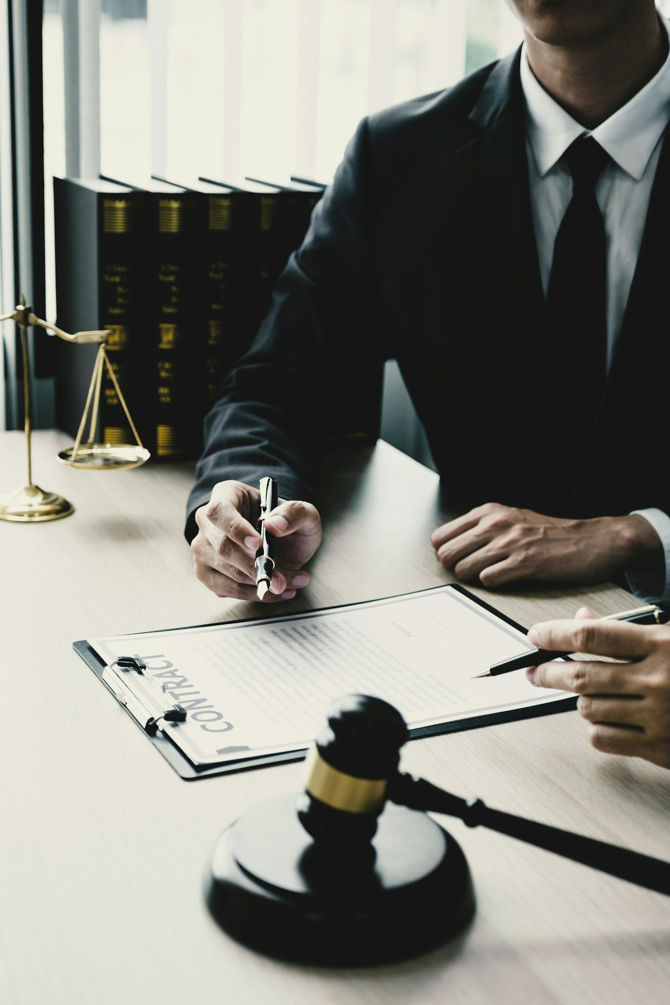 lawyer hand holding pen and providing legal consult business dispute to businessman at the office